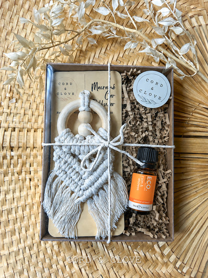 Gift set with macrame car diffuser and essential oil bottle on a woven surface