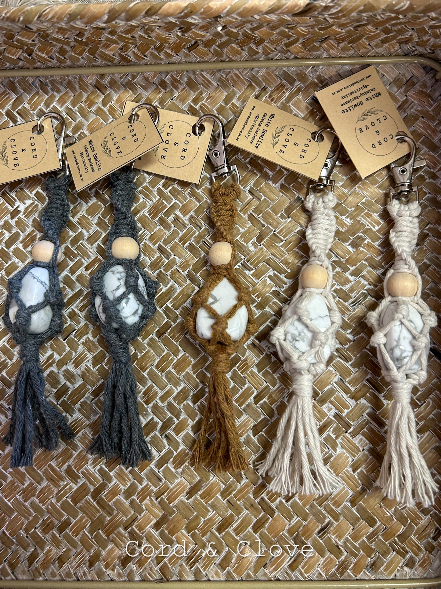 Set of macrame crystal keychains with tags on a textured surface