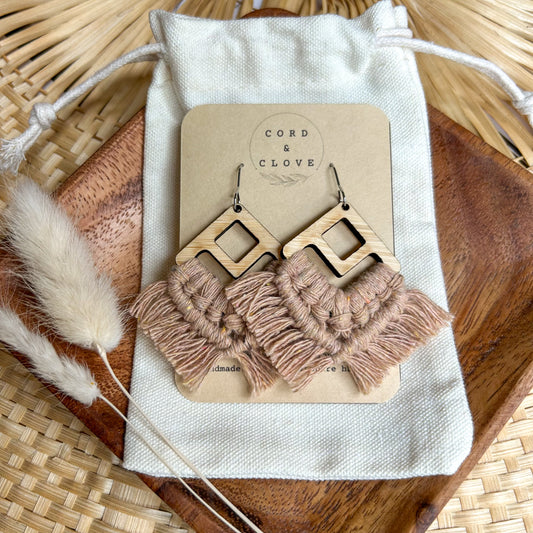Pair of earrings with tassel details on a 'Cord & Clove' branded card, placed on a textured surface.