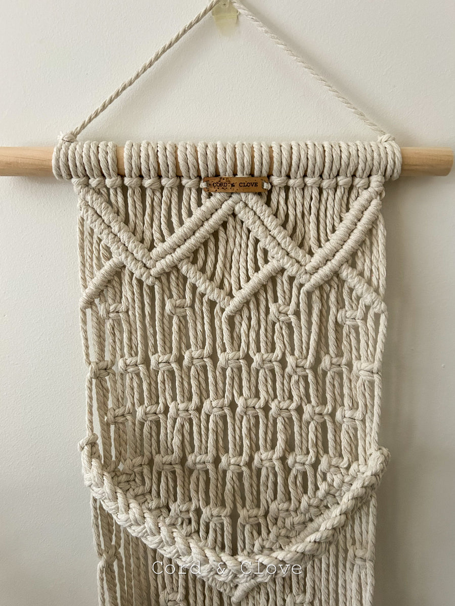 Macrame wall hanging with geometric pattern on a white background