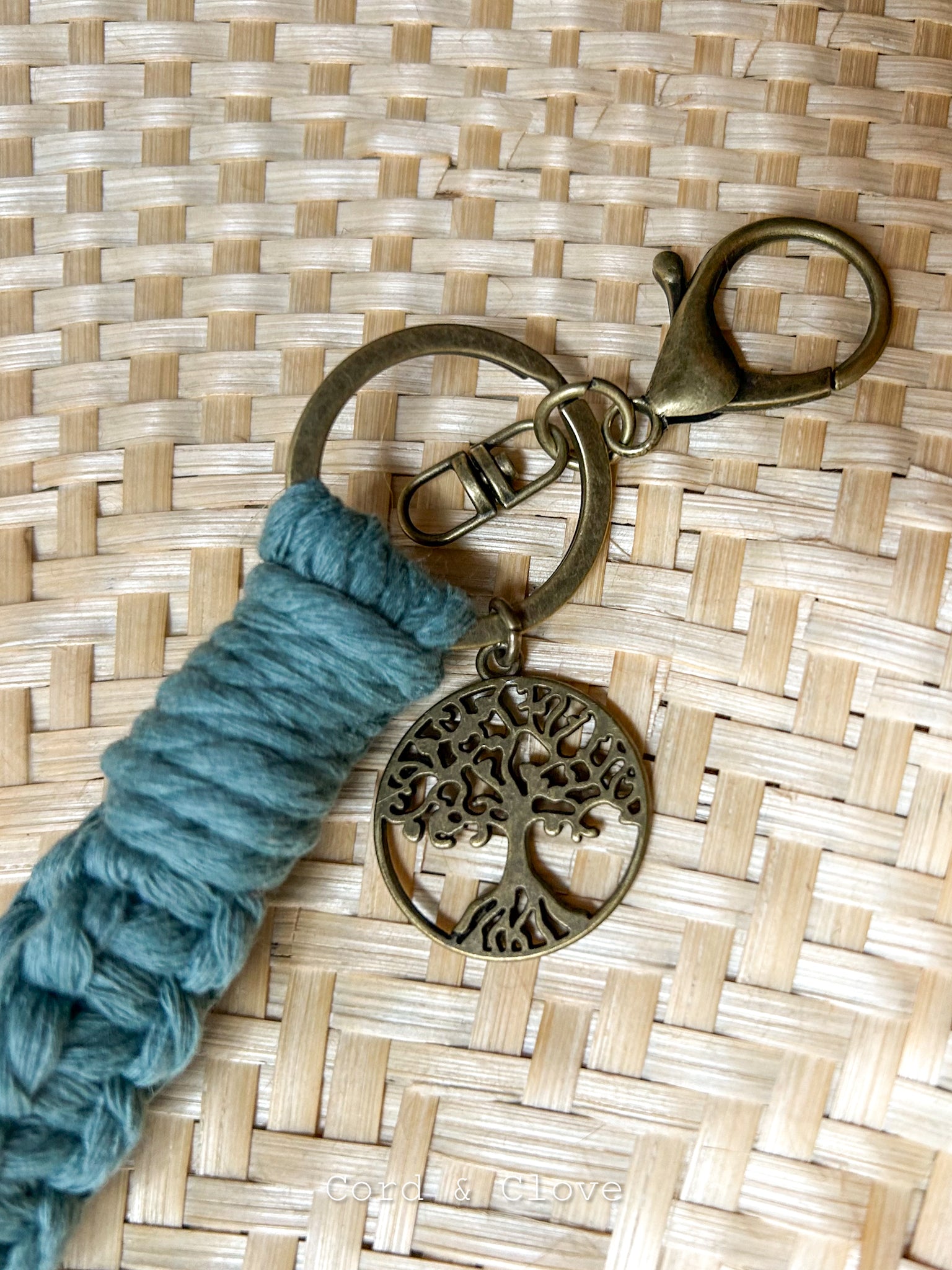 Keychain with blue cord and tree-of-life charm on a woven surface