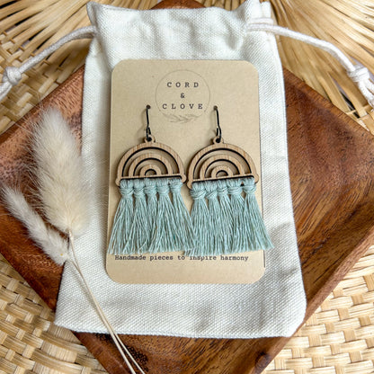 Wooden rainbow earrings with tassels on a 'Cord & Clove' branded card, placed on a textured surface.
