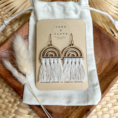 Pair of wooden rainbow tassel earrings on a 'Cord & Clove' branded card with dried plants and wood in the background.
